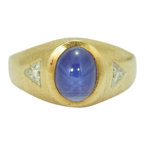 A gold ring set with a star sapphire and diamonds
