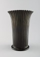 Just Andersen: f. Godhavn, Grønland 1884, d. Glostrup 1943.  
Vase af patineret diskometal, støbt med vertikalt riflet mønster.