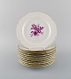 Tolv antikke Meissen tallerkener i håndmalet porcelæn med lilla blomster og 
guldkant. Ca. 1900.
