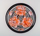 Large round Hermès porcelain serving dish decorated with red flowers on a black 
and white patterned background. 1980s.
