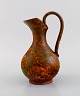 European studio ceramicist. Unique pitcher in glazed stoneware. Beautiful glaze 
in orange shades. 1960s / 70s.
