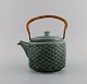 Jens H. Quistgaard (1919-2008) for Nissen Kronjyden. Azur teapot in glazed 
stoneware with wicker handle. 1960s.
