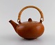 Eva Stæhr-Nielsen for Saxbo. Glazed stoneware teapot with wicker handle. 
Beautiful glaze in red-brown shades. Mid 20th century.
