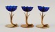 Gunnar Ander for Ystad Metall. Tre lysestager i messing og blåt kunstglas formet 
som blomster. 1950