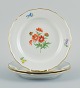 Meissen, Germany. Three porcelain plates hand-painted with various floral motifs 
and gold rim.