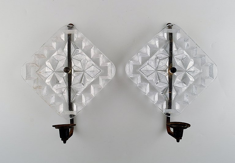 Erik Höglund for Kosta Boda. Two wall candle holders in clear art glass and 
wrought iron. Ca. 1970.
