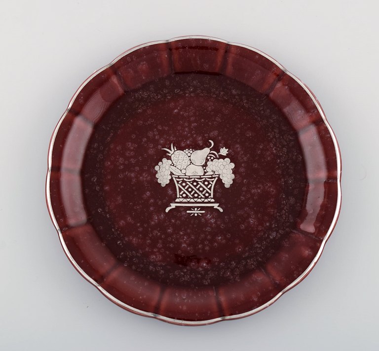 Wilhelm Kåge for Gustavsberg. Rare red Argenta dish in glazed ceramics decorated 
with fruit basket in silver inlay. Sweden 1940