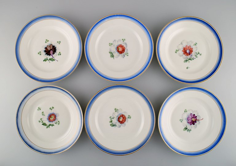 Seks antikke Royal Copenhagen tallerkener i håndmalet porcelæn med blomster og 
blå kant med guld. Modelnummer 592/9051. Sent 1800-tallet. 
