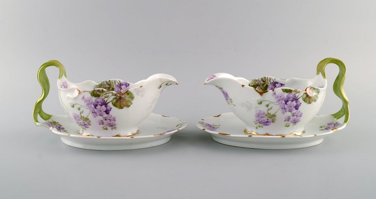 Rosenthal, Tyskland. To Iris sovsekander i håndmalet porcelæn med blomster og 
guldkant. Håndtag modeleret som bladværk. 1920