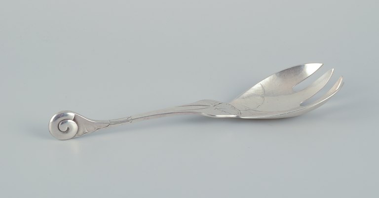 Early and rare Georg Jensen "Ornamental" pattern serving-fork chased with 
foliage and with a spiral shell finial. Sterling silver.