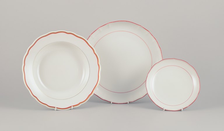 Meissen, Germany. Three-piece porcelain set consisting of a large bowl, a deep 
plate, and a plate. Decorated with coral red and gold-colored trim. Art Deco.